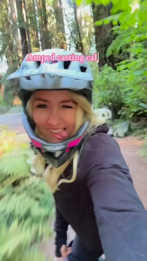 Rider in a full-face helmet filming a selfie on a forest trail